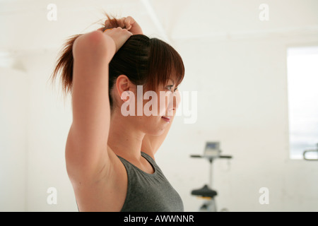 Young woman tying hair back in gym Stock Photo