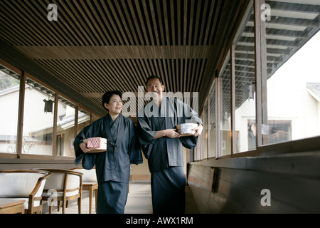 Elderly couple walking in corridor, holding buckets, smiling Stock Photo