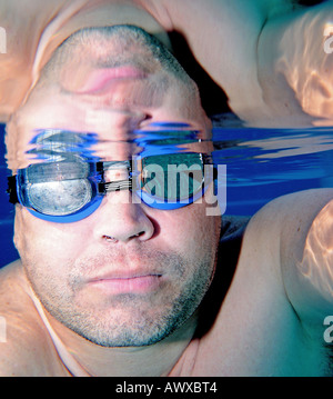 Male middle aged swimmer as seen underwater with blue goggles on Stock Photo