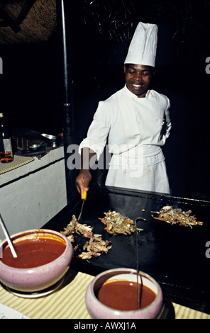 Chef cooking local game meat on a metal plate Victoria Falls Hotel Zimbabwe Africa Stock Photo