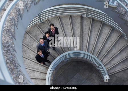Four business associates standing on spiral staircase, portrait Stock Photo