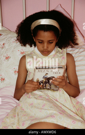 Little black girl reading Jill's Pony Trek book. Stock Photo