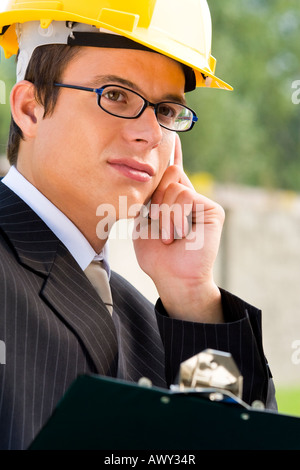 A young male manager in hard hat making a phone call Stock Photo