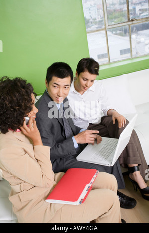 Business People Sitting on Sofa using Laptop and Cell Phone Stock Photo