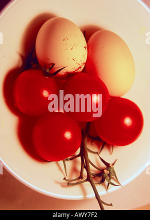 Two and eggs and some tomatoes in a white bowl Stock Photo