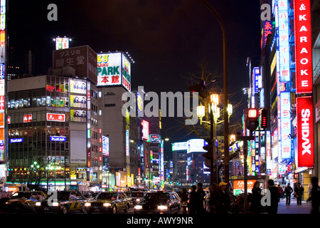 Busy street scene at night with many bright glowing signs on buildings along Yasukuni Dori in Shinjuku Tokyo Japan Stock Photo