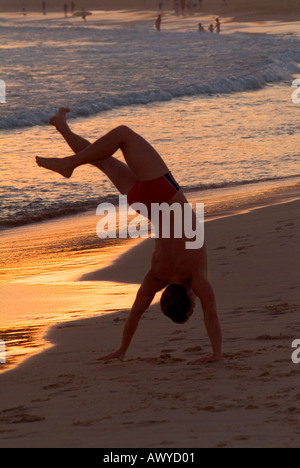 Man doing handstand on Bondi Beach in the late afternoon in Sydney Stock Photo
