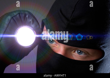 man with flashlight wearing ski mask breaking into bank vault Stock Photo