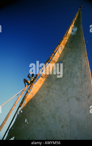 Sailor waving from observation post on mast of arabic sailing dhow somewhere off the coast of Zanzibar Tanzania No MR no PR Stock Photo