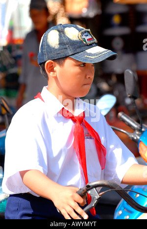Asia Far East Vietnam , Hoi An market , one young boy riding on bike in traditional communist style school uniform & baseball cap Stock Photo