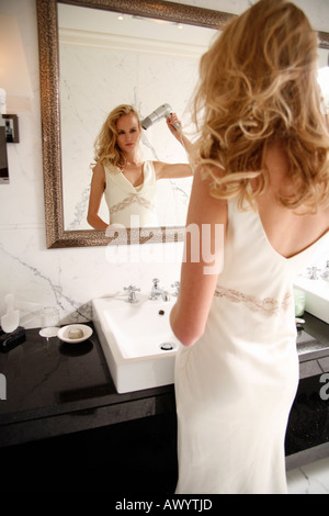 Woman drying her hair in bathroom Stock Photo