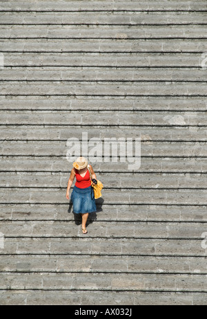 A tourist wearing a hat walks down stone stairs in Amalfi, Italy Stock Photo