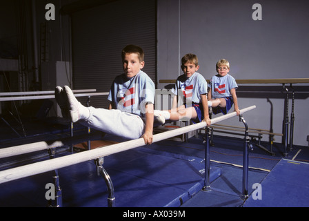 Three young male gymnasts work out on parallel bars Stock Photo