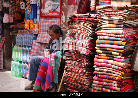 A man mends a blanket for sale in the Witches' Market of La Paz, Bolivia. Stock Photo