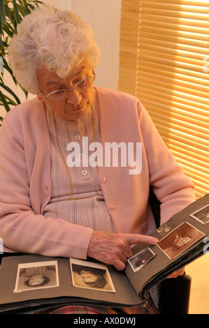 Elderly woman looking through photo album filled with old family ...
