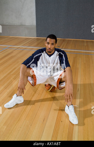 A young man looking serious sitting on a basketball Stock Photo