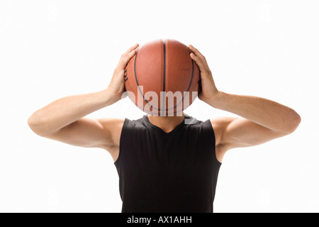 A studio portrait of a young man holding a basketball in front of his face Stock Photo