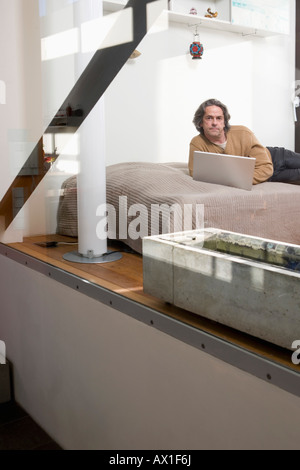 A man lying on his bed using a laptop Stock Photo