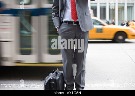 A businessman standing on a sidewalk and using a mobile phone Stock Photo
