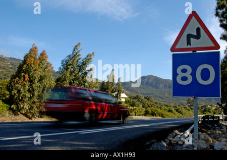 Speeding car on a highway with speed limit road signs at 80 km per hour and warning of bends in the road, Spain Stock Photo