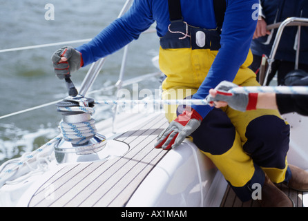 A person turning a cable winch on a yacht Stock Photo