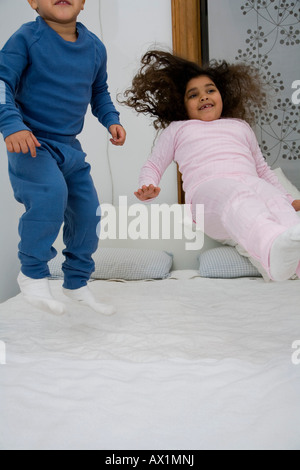 Two children jumping on a bed Stock Photo