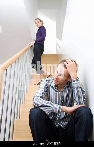 A mid adult couple arguing on a staircase Stock Photo