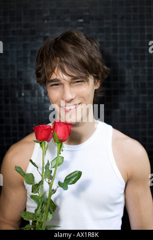 A young man holding two red roses and smiling Stock Photo