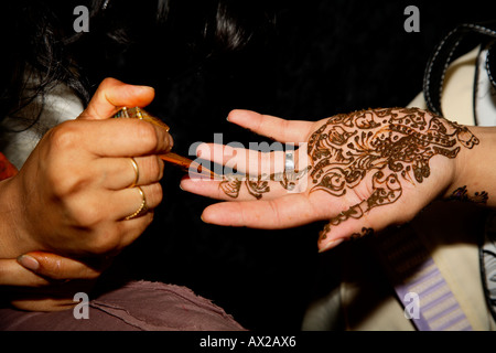 Young woman painting henna tattoo (mehndi) on hand at Asian Lifestyle Show, London Olympia, 2006 Stock Photo
