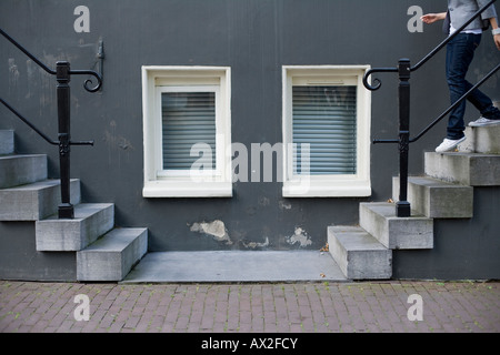 two windows between two stairs in left and right sides with a person descending on the right Stock Photo