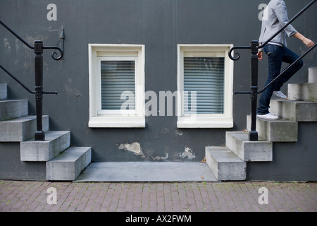 two windows between two stairs in left and right sides with a person ascending on the right Stock Photo
