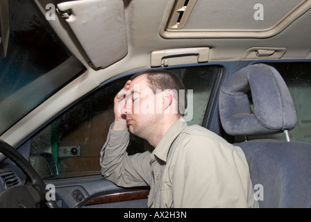 man looking sad in his car in garage Stock Photo