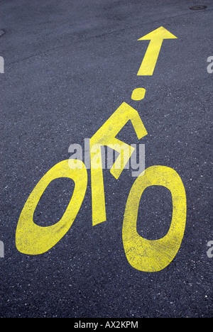 yellow painted cyclist sign on tarmac road Stock Photo