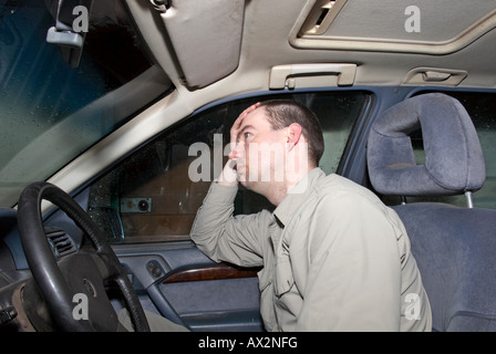 man looking sad in his car in garage Stock Photo