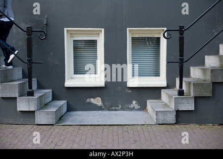 two windows between two stairs in left and right sides with a person ascending on the left Stock Photo