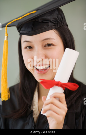 Asian woman wearing graduation cap and holding diploma Stock Photo
