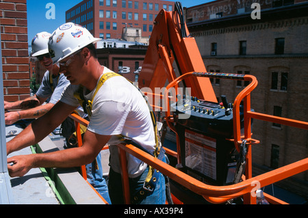 Construction workers in cherry picker installing windows in high rise building Denver Colorado USA Stock Photo