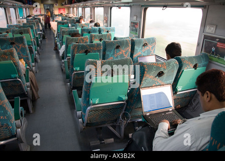 A man working on his laptop in the passenger compartment on an Indian express train Stock Photo