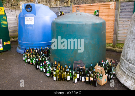 Recycling wine bottles can bank in a large container.  Recycling centre glass bottles facility empty alcohol bottles & festive overfill wheelie bins. Stock Photo