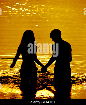young couple walking in surf at beach Stock Photo