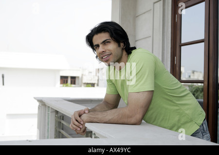 Young man standing on a balcony and smiling Stock Photo