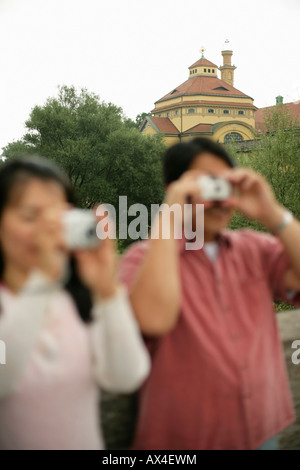 Asian heterosexual couple is standing on a bridge and is taking pictures, focus on background Stock Photo