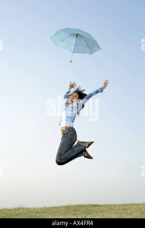 Side profile of a young woman jumping in a park Stock Photo