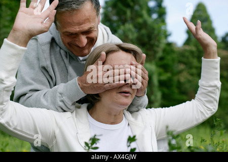 Mature man covering woman's eyes Stock Photo