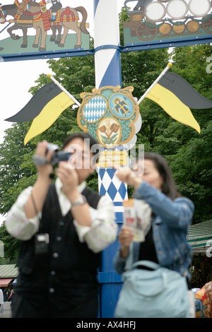 Young Asian woman and man with camera standing in front of a maypole, selective focus Stock Photo