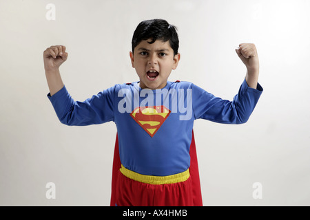 Portrait of a boy wearing superman costume and flexing his muscles Stock Photo