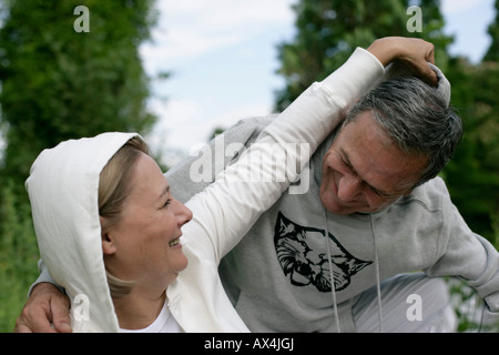 Mature woman putting a hood on man's head Stock Photo