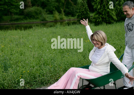 Mature man pushing woman in a wheelbarrow Stock Photo