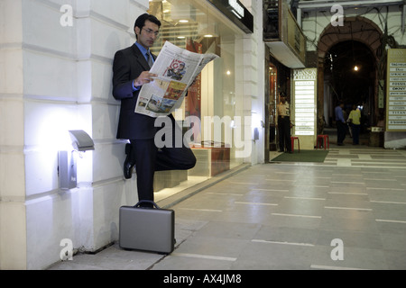 Businessman reading newspaper in a shopping mall Stock Photo