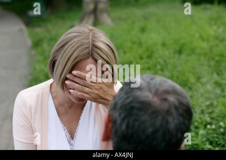 Mature woman covering her eyes in front of man Stock Photo
